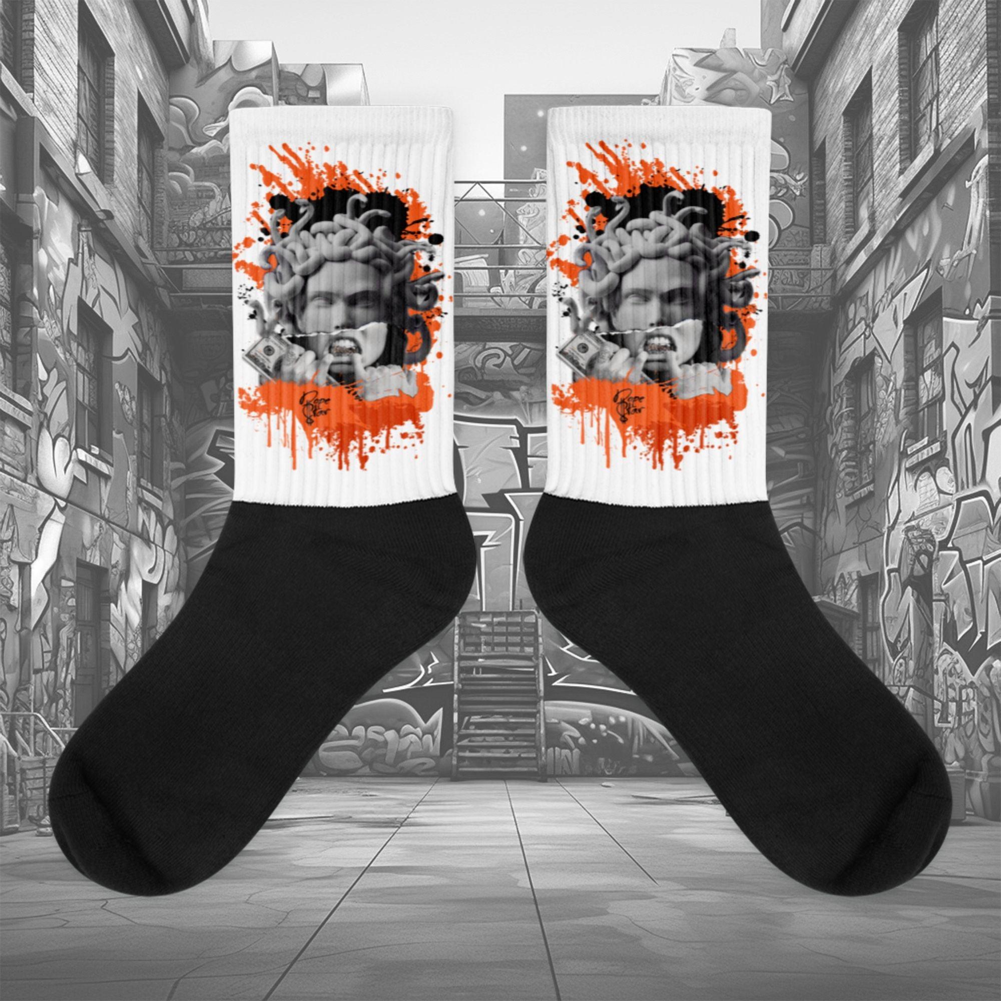 Showcases the view of the socks, highlighting the vibrant ' MEDUSA' design, which perfectly complements the Air Jordan 12 Retro WNBA All-Star Brilliant Orange sneakers. The intricate pattern and color scheme inspired by the  theme are prominently displayed.  Focusing on the ribbed leg , cusioned bottoms and the snug fit of the socks. This angle provides a clear view of the texture and quality of the material blend.