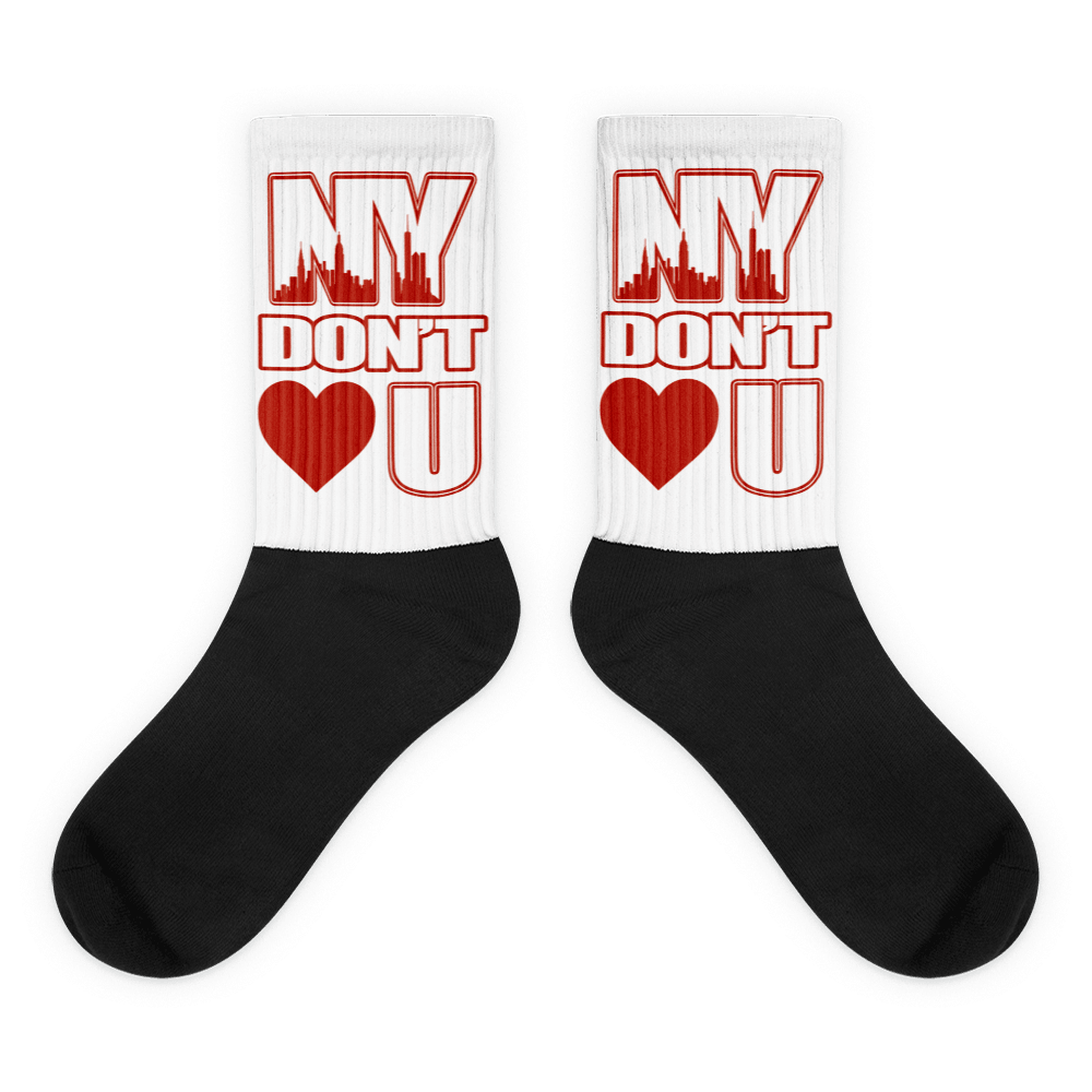 Showcases the view of the socks, highlighting the vibrant ' NY Don’t Love U ' design, which perfectly complements the Air Jordan 11 Cherry sneakers. The intricate pattern and color scheme inspired by the  theme are prominently displayed.  Focusing on the ribbed leg , cusioned bottoms and the snug fit of the socks. This angle provides a clear view of the texture and quality of the material blend.