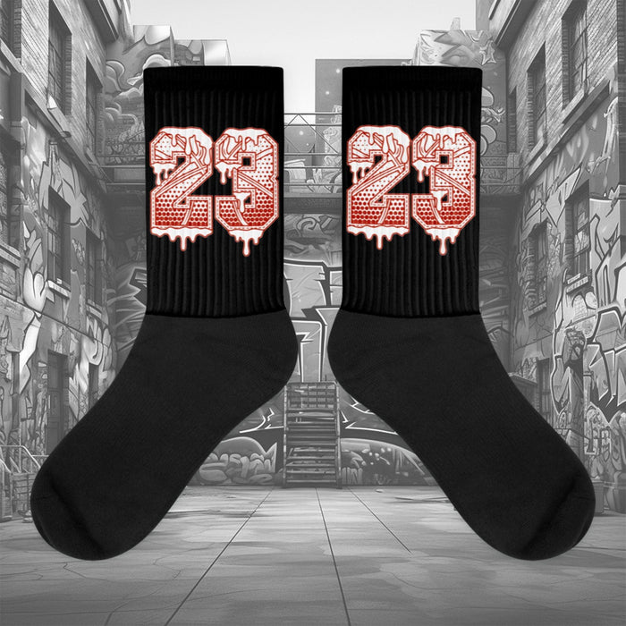  Showcases the view of the socks, highlighting the vibrant ' 23 Ball ' design, which perfectly complements the Air Jordan 11 Cherry sneakers. The intricate pattern and color scheme inspired by the  theme are prominently displayed.  Focusing on the ribbed leg , cusioned bottoms and the snug fit of the socks. This angle provides a clear view of the texture and quality of the material blend
